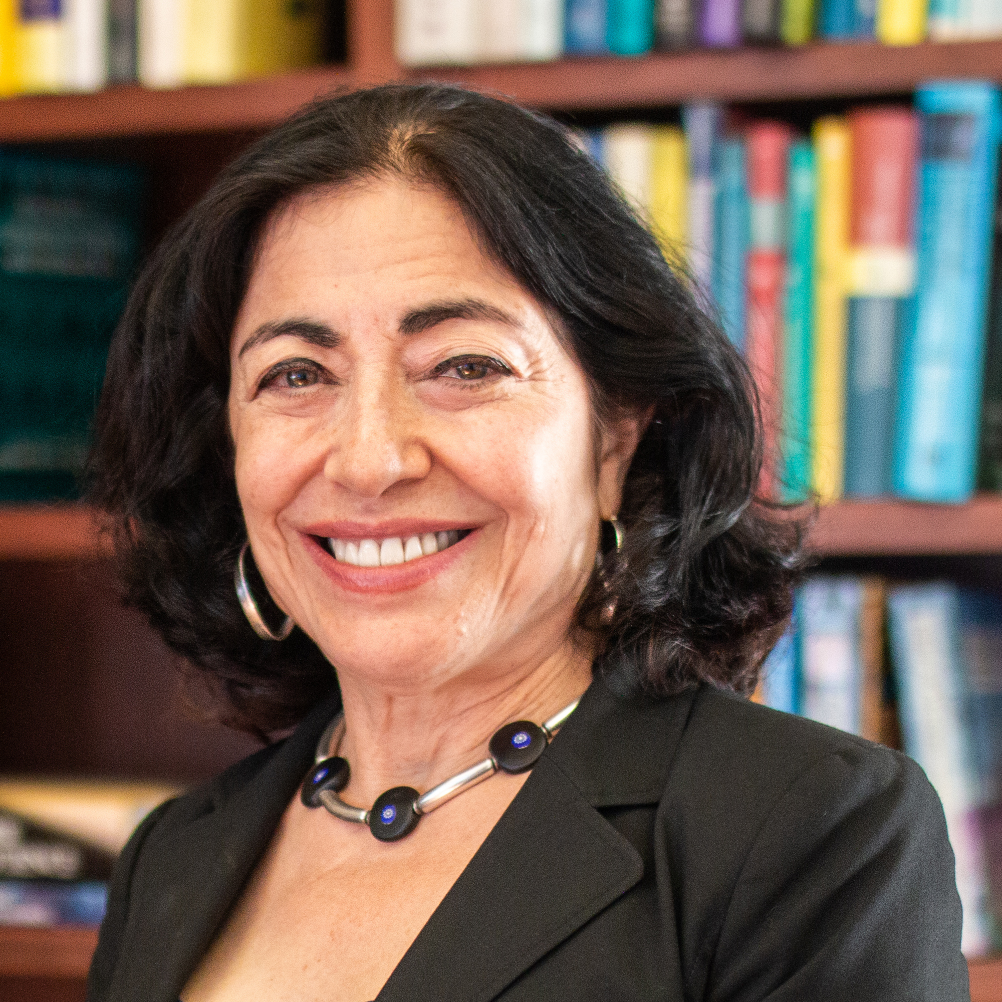 Portrait of Dean Jennifer Chayes wearing a black suit and posing in front of a bookshelf