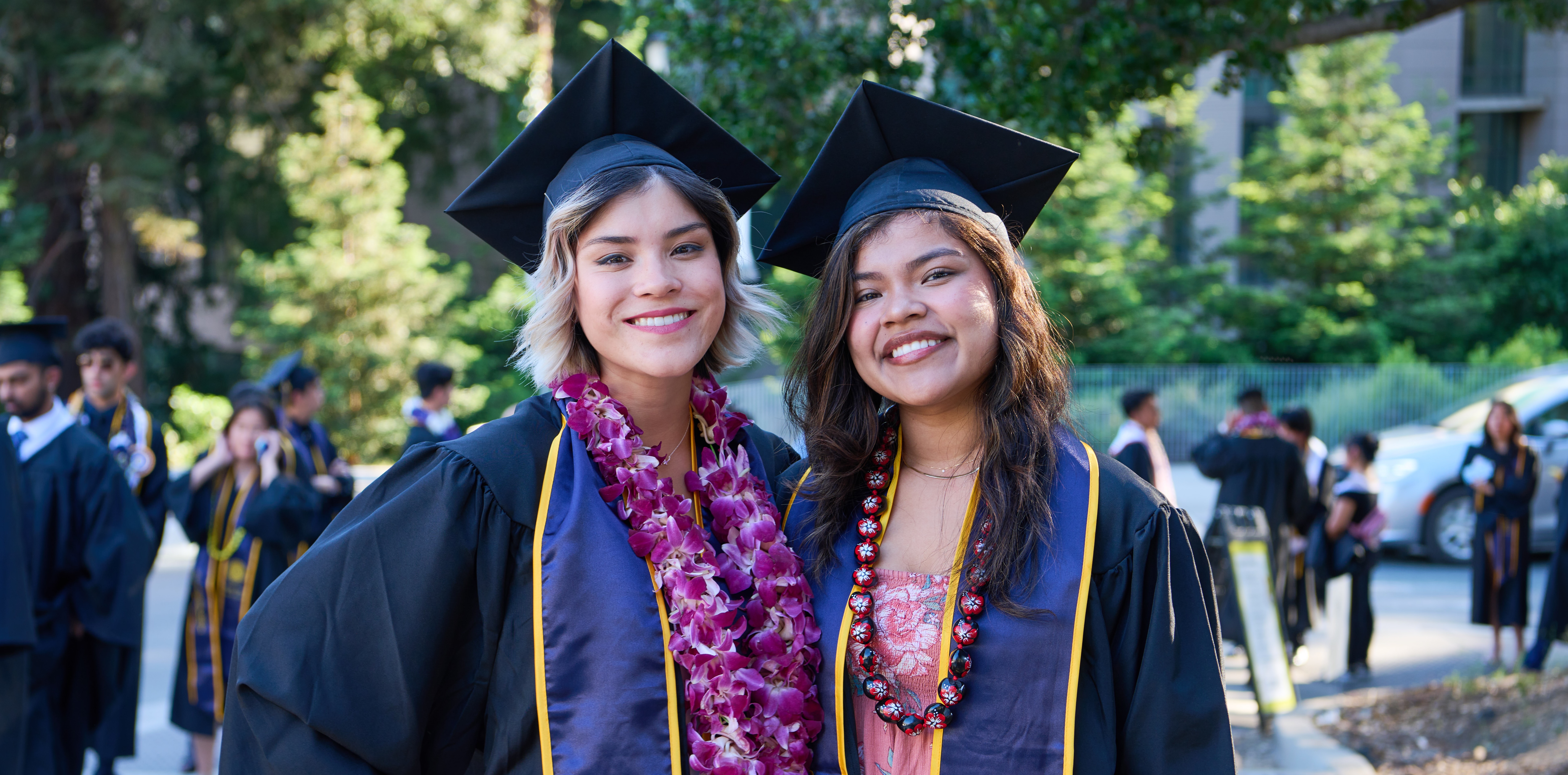 Two latina students pose in graduation caps and gowns