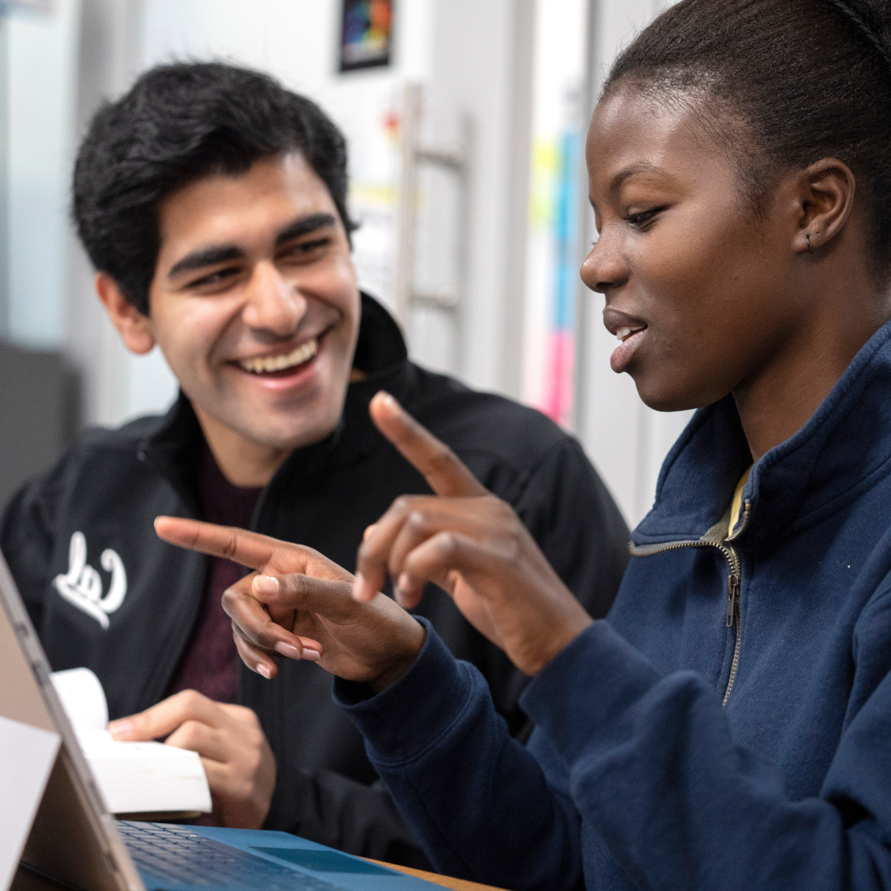 Two people engaged in conversation in front of a laptop 