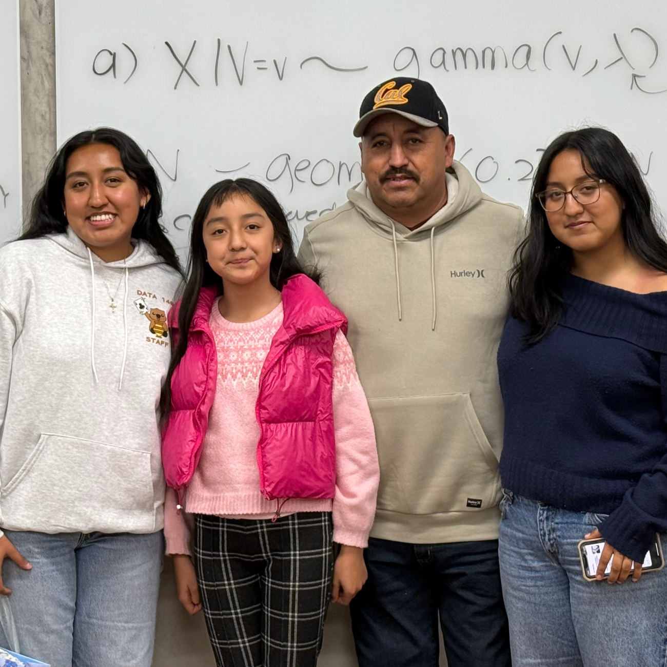 Data science major, Fatima Gonzalez Perez, stands in front of classroom white board with family