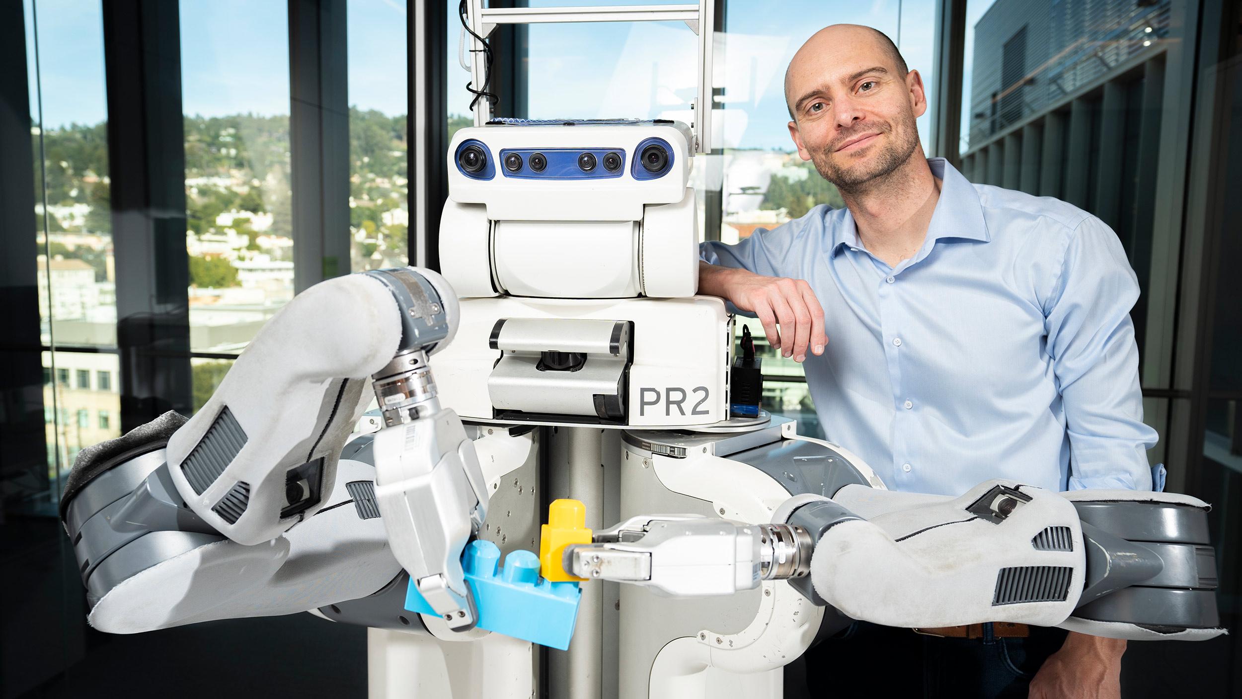 Pieter Abbeel standing next to BRETT, the Berkeley Robot for the Elimination of Tedious Tasks. (Photo by Adam Lau, Berkeley Engineering)