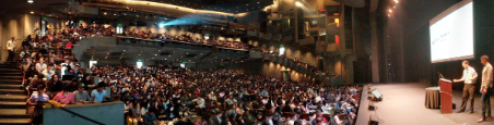 Panoramic shot of lecturer in Zellerbach hall for Data 8 with many students filling out seats 