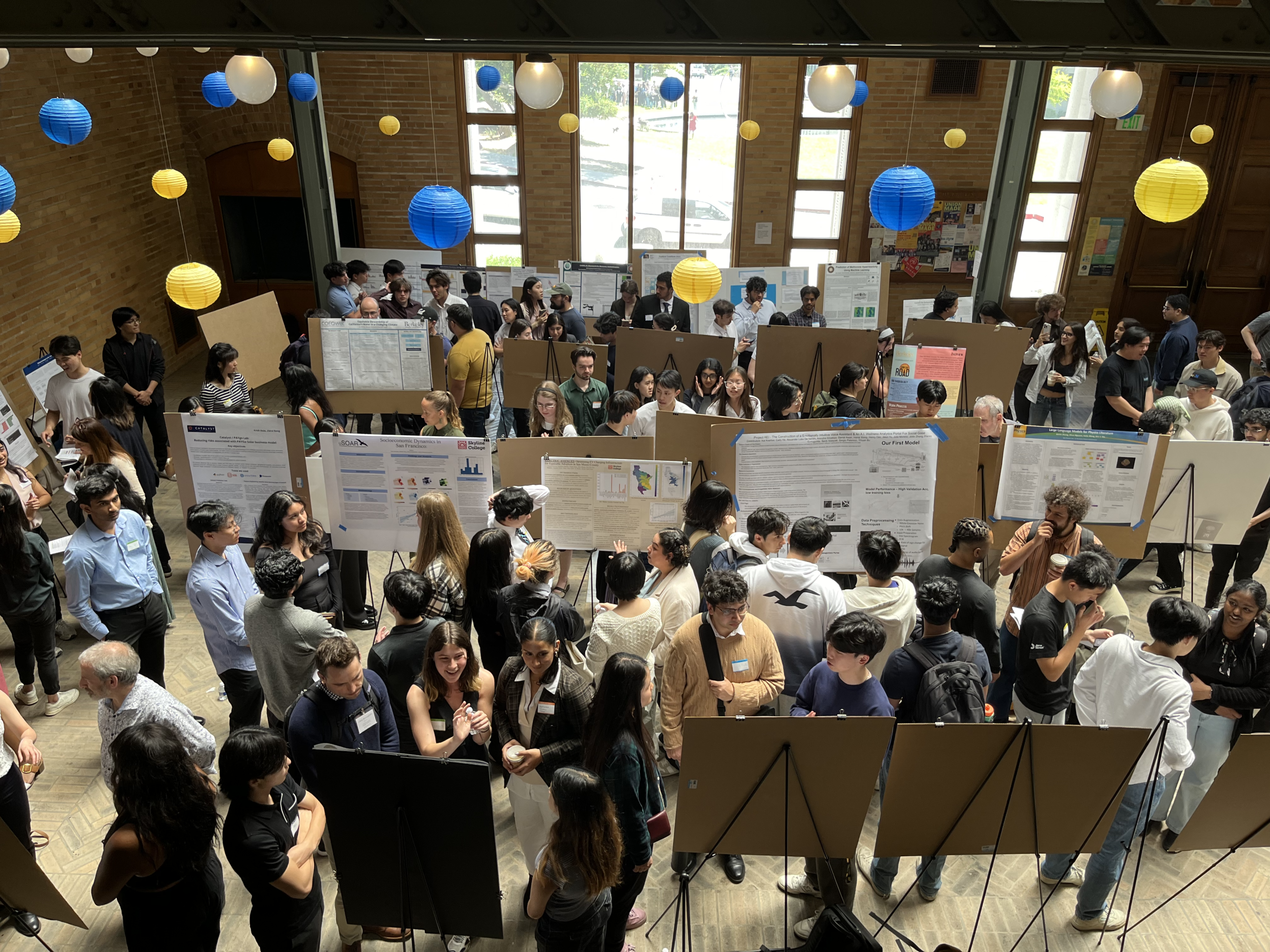 Students presenting research posters in crowded lobby of Hearst Memorial Mining Building at 2024 Data Science Discovery Symposium