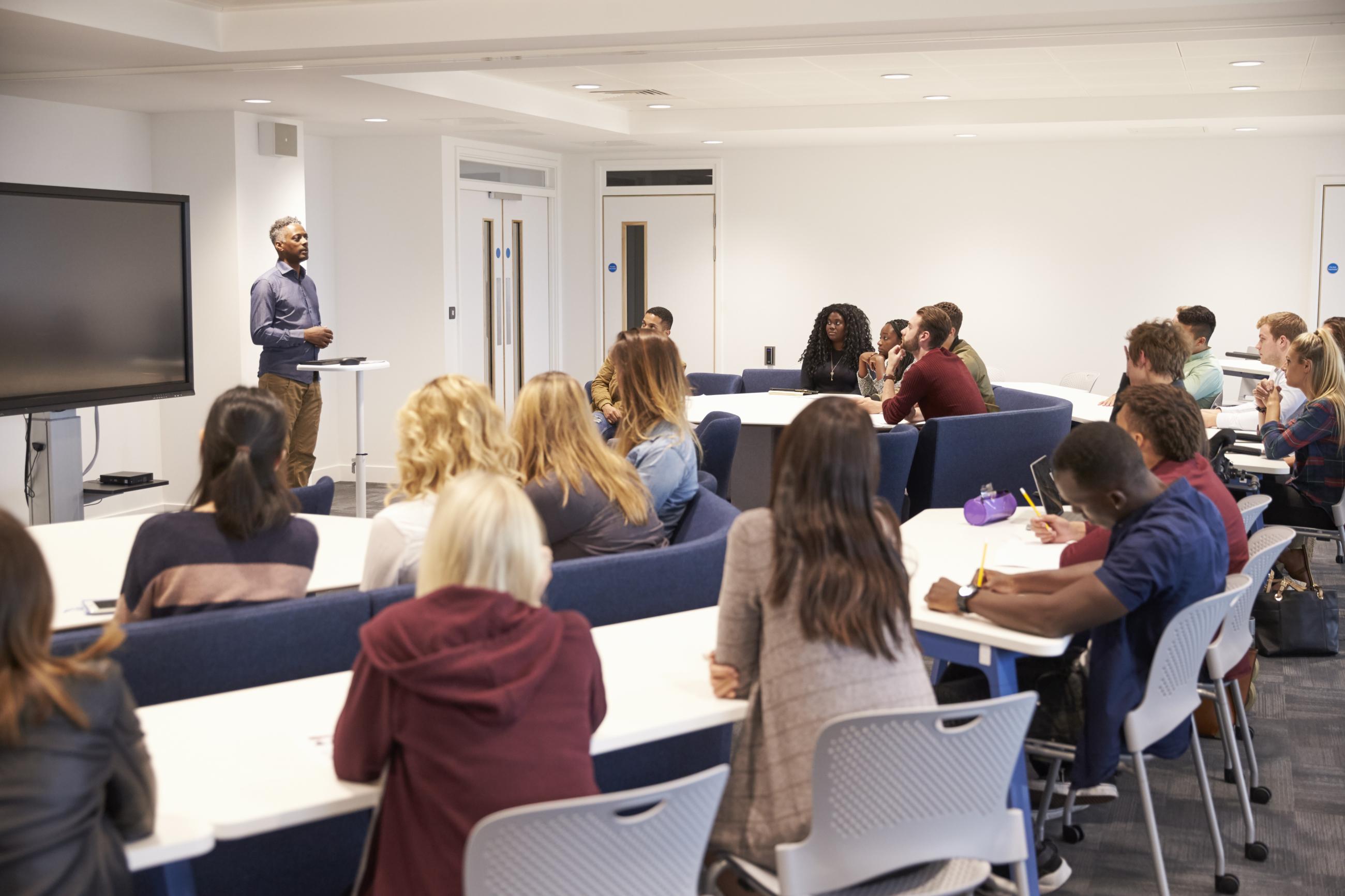 An instructure speaks to a small classroom of attentive college students