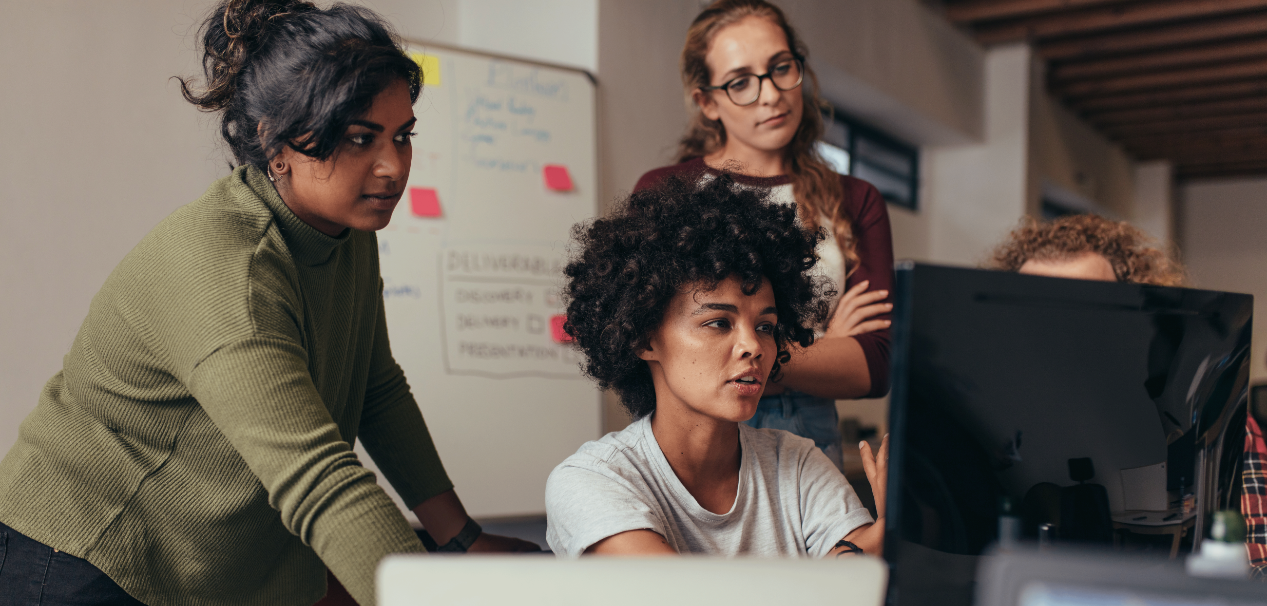 Four people standing in half circle around monitor