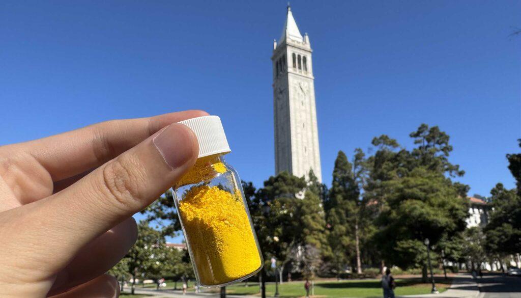 A vial of COF-999, which is yellow, with UC Berkeley’s landmark campanile in the background.