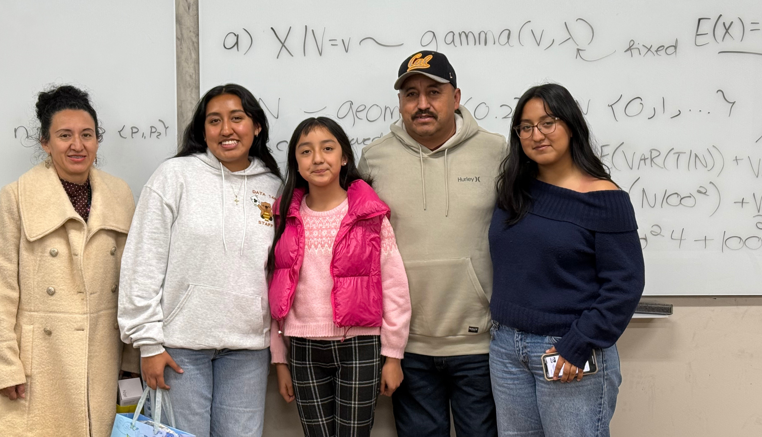 Data science major, Fatima Gonzalez Perez, stands in front of classroom white board with family