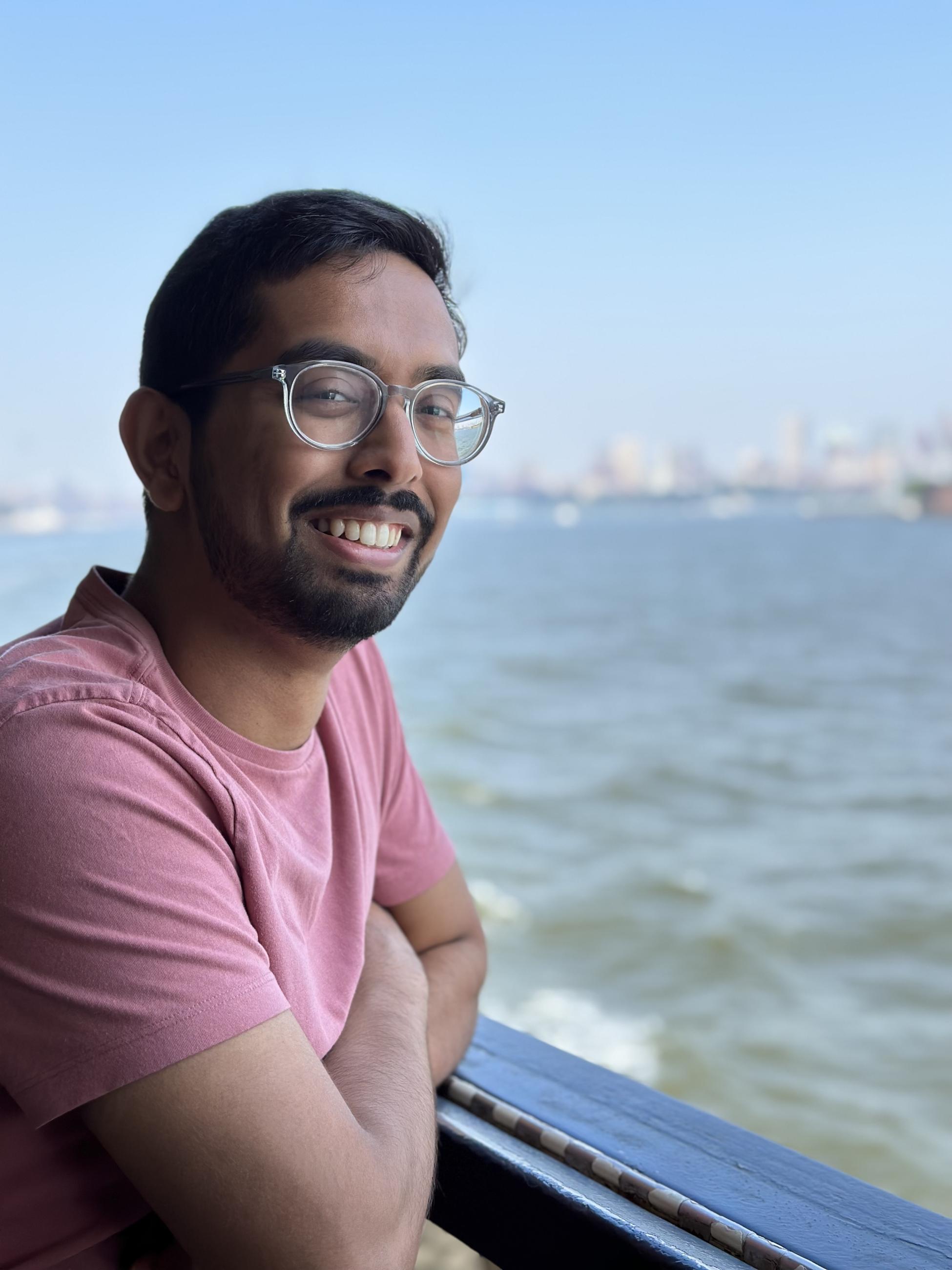 Shoumik Jamil, B.A. '19, leans against balcony above ocean with city in distance